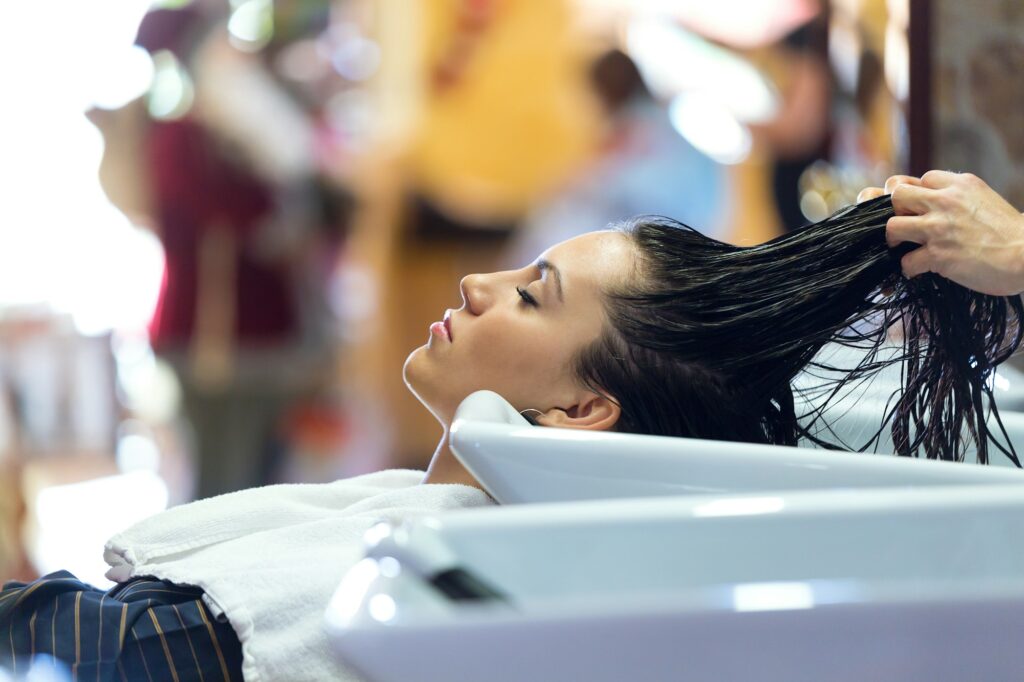 Beautiful young woman washes hair in a beauty salon.