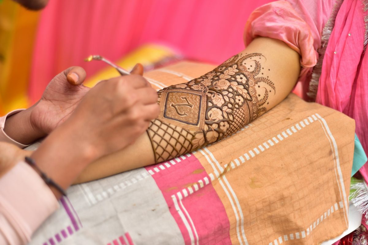 Artist applying henna tattoo on women hands