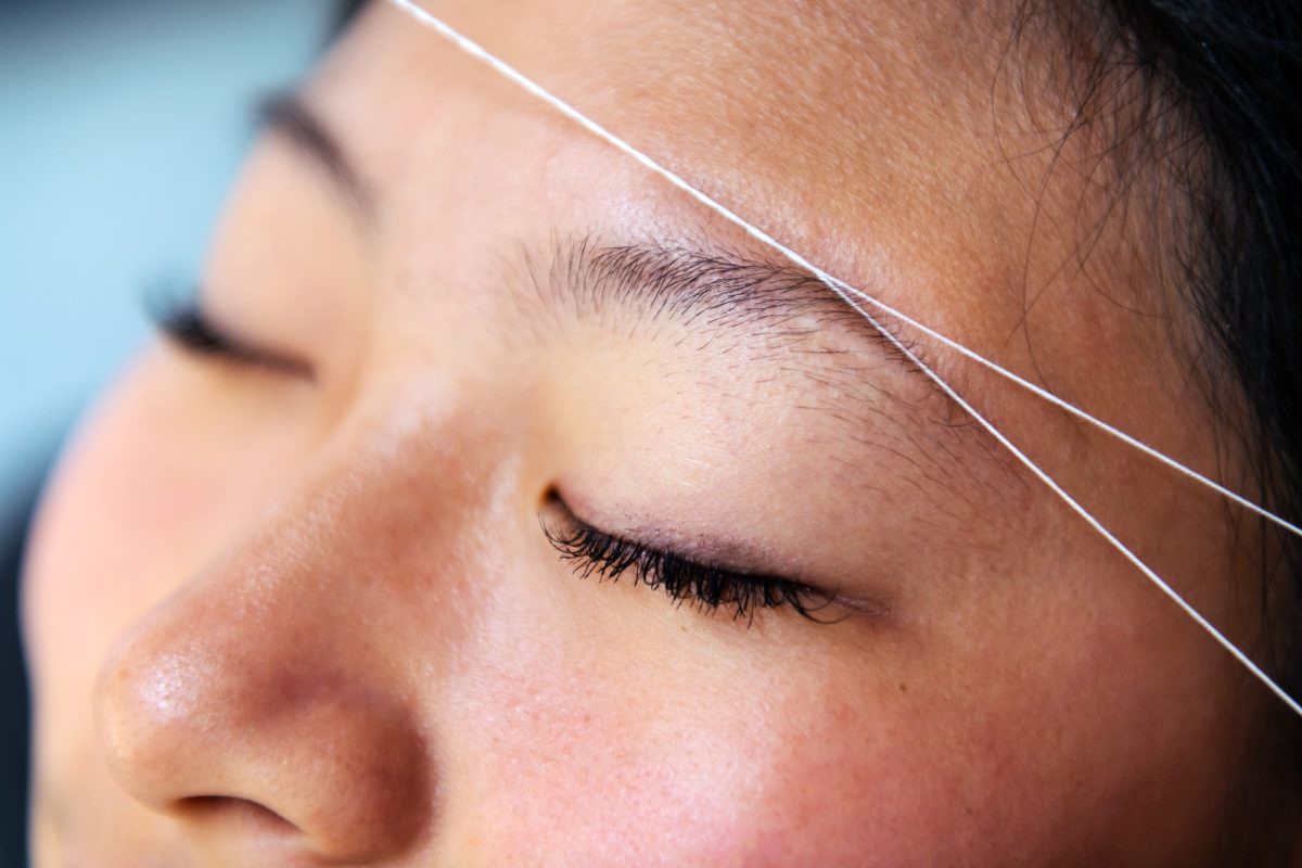 eyebrow waxing with threading on a young woman