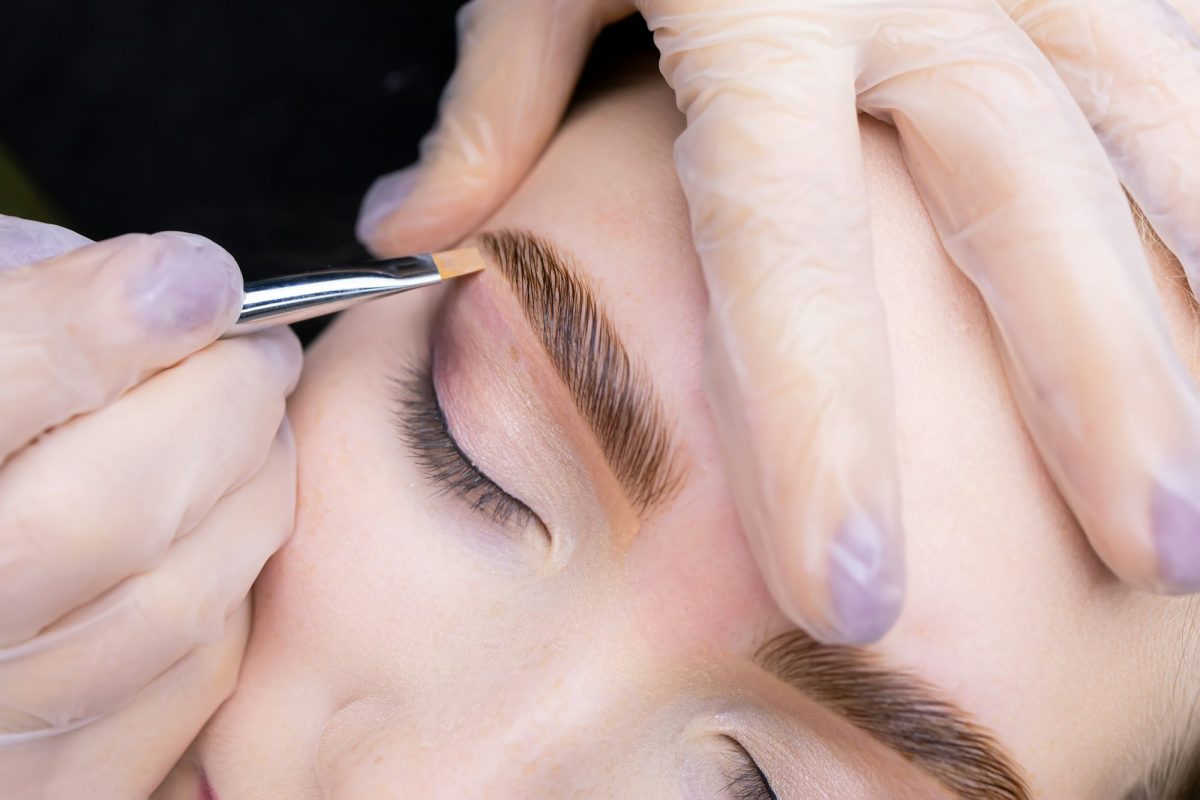 laminated eyebrows after coloring and correction, the master applies a brush and a toning cream