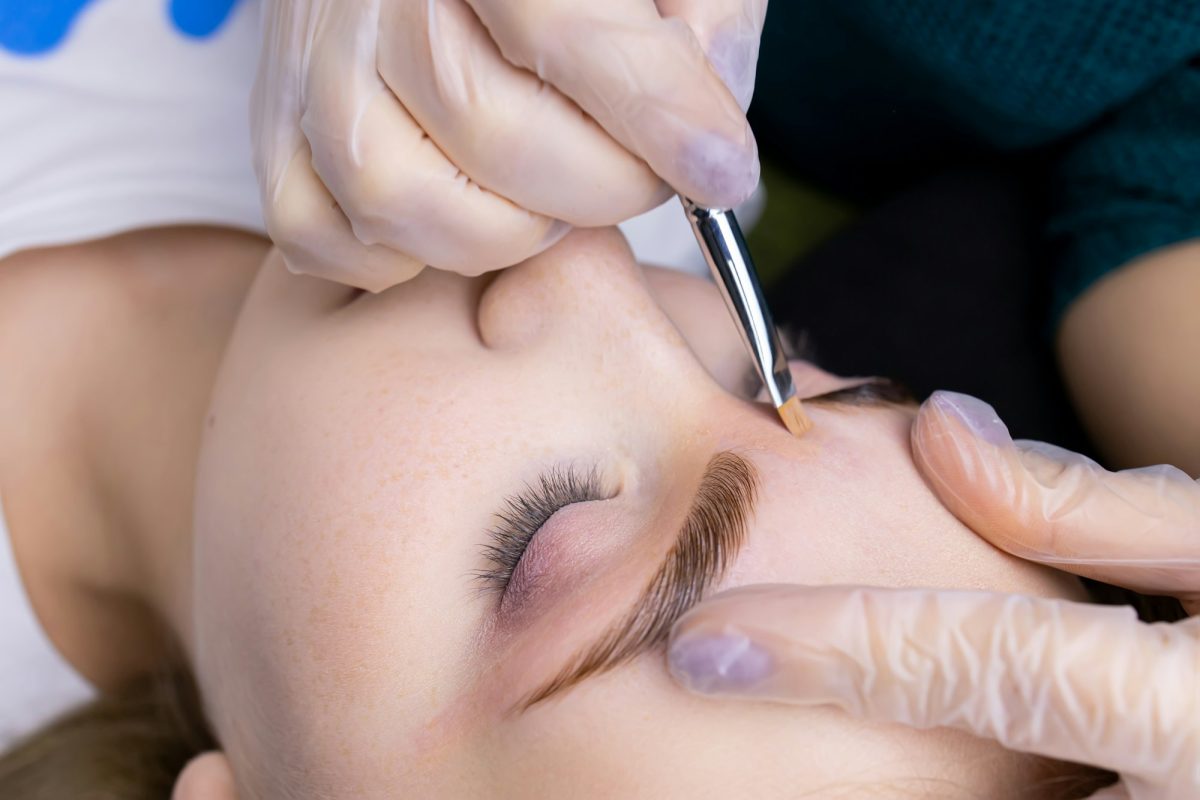 the master in white gloves holds the eyebrow of the model after the lamination procedure