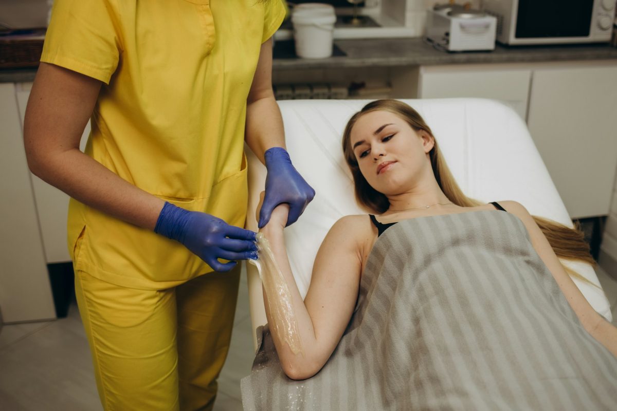 Waxing arms in beauty salon. Woman hands